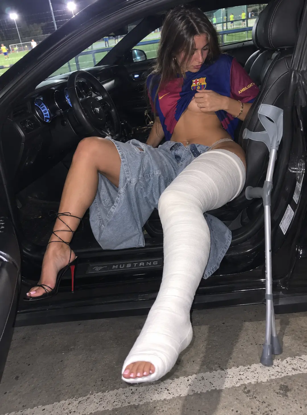 Football night scene in a car with a realistic long leg cast and crutch