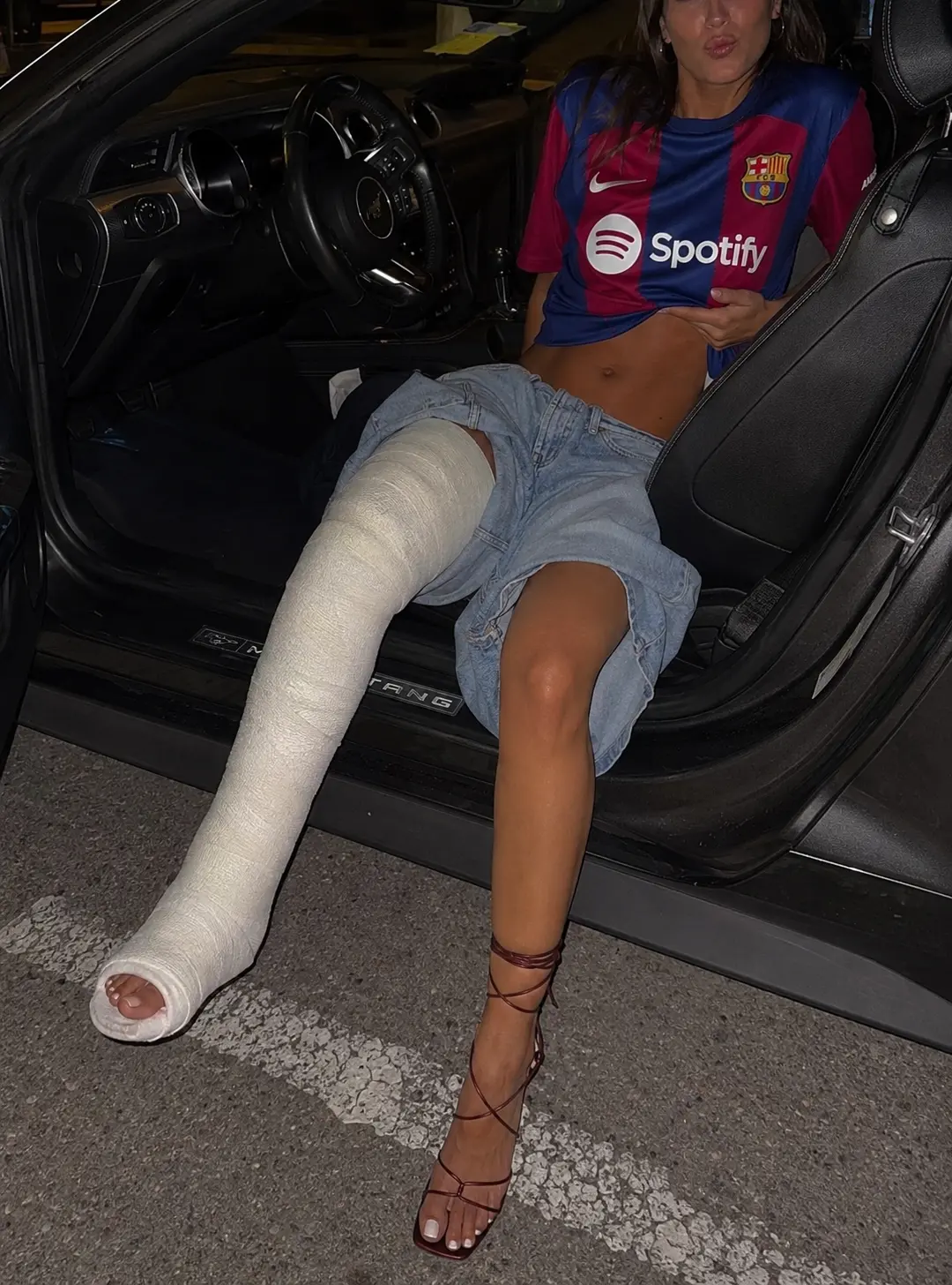 Nighttime football outfit scene beside a car with a long leg cast